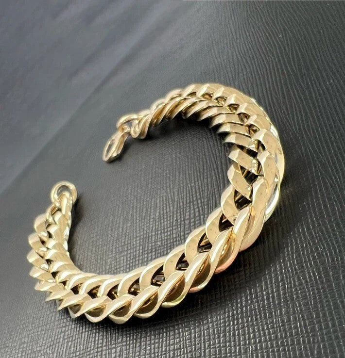 Gold chain bracelet on a dark textured surface available on the TX.ORO website.
