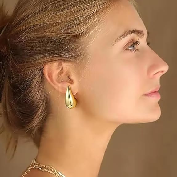 Close-up of a woman wearing a gold earring with a soft background available on the TX.ORO website.