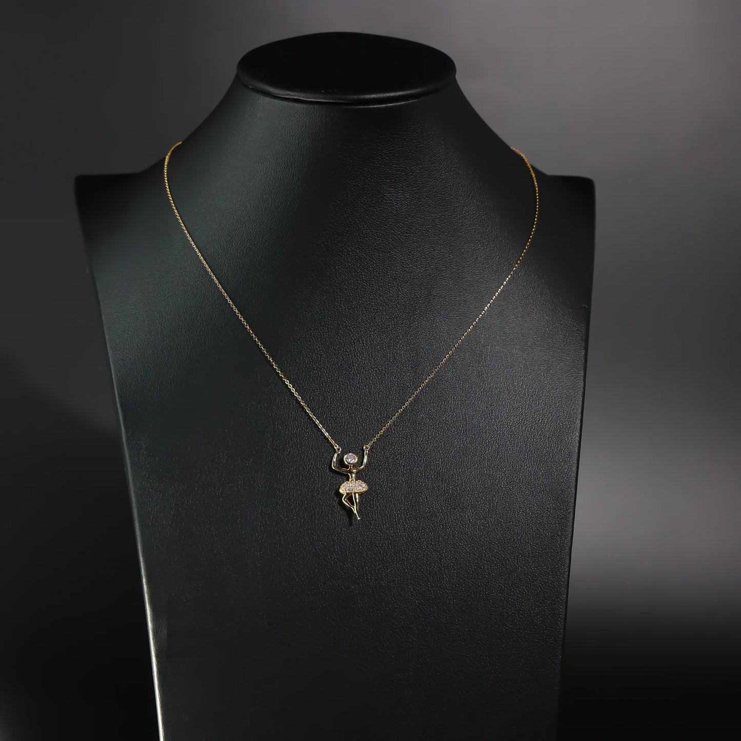 Gold necklace with a pendant on a black mannequin bust against a dark background available on the TX.ORO website.