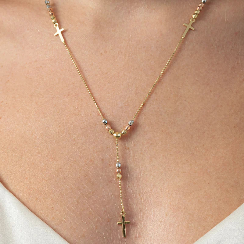 Gold necklace with crosses on a person wearing a white top available on the TX.ORO website.
