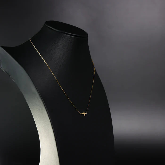 Gold necklace on a black mannequin bust against a dark background available on the TX.ORO website.