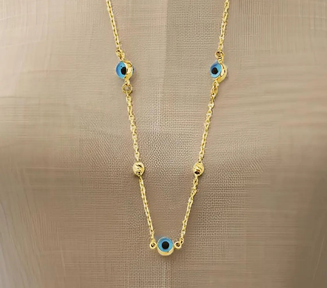 Gold necklace with blue evil eye charms on a beige background available on the TX.ORO website.