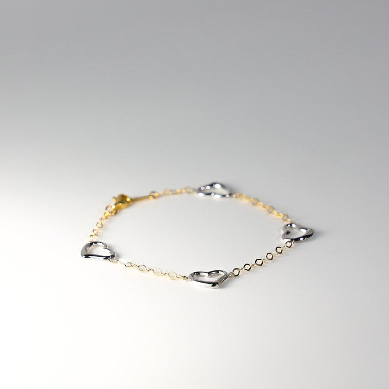 Gold and silver bracelet on a light gray background available on the TX.ORO website.