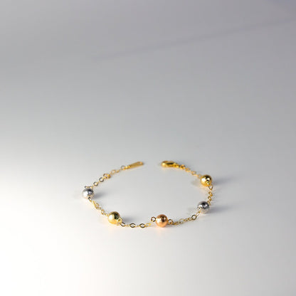 Gold bracelet with spherical beads on a gray background available on the TX.ORO website.