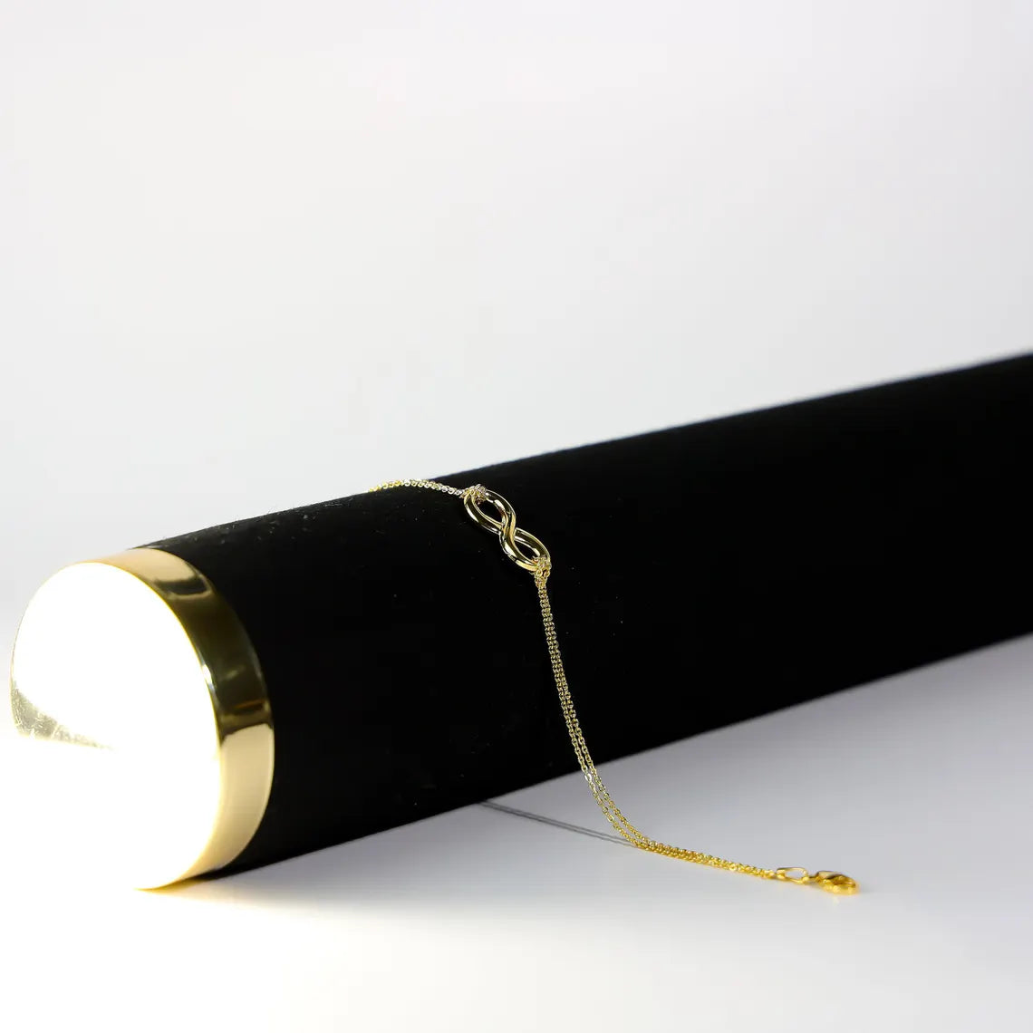 Gold chain on a black cylindrical object with a white background available on the TX.ORO website.