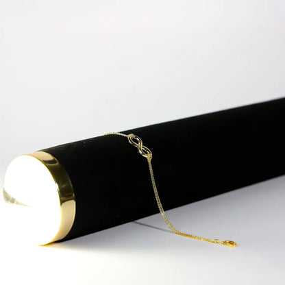 Gold chain on a black cylindrical object with a white background available on the TX.ORO website.