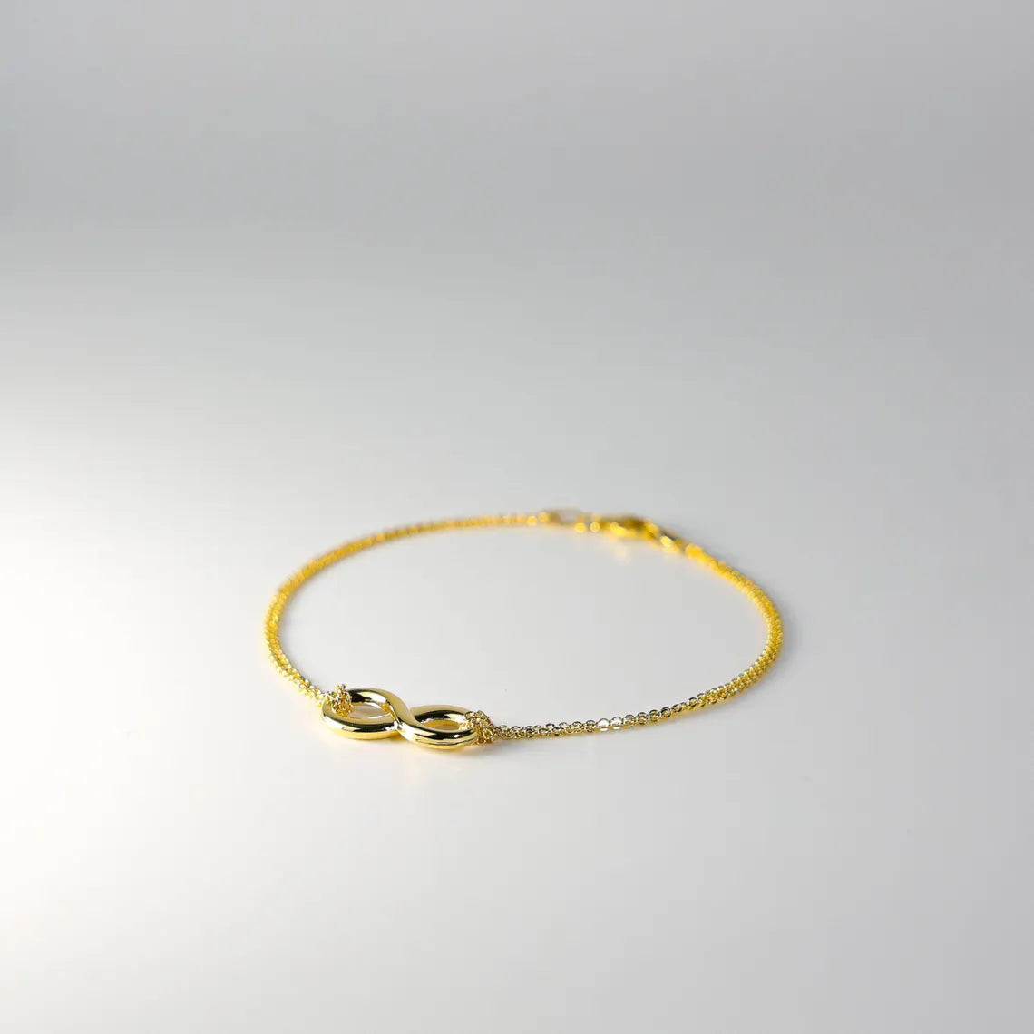 Gold bracelet with a unique clasp design on a light gray background available on the TX.ORO website.