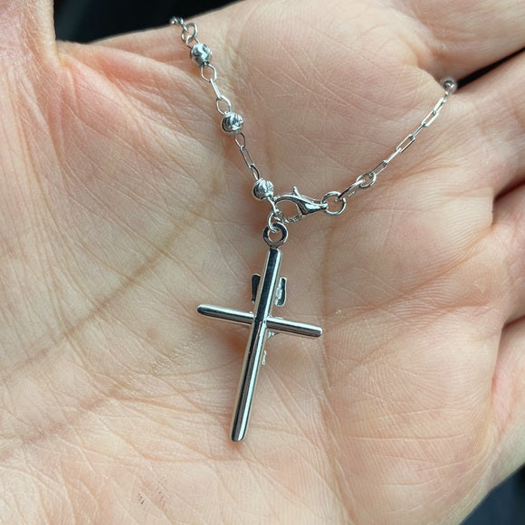 Silver cross necklace on a hand availabe on TX.ORO website.