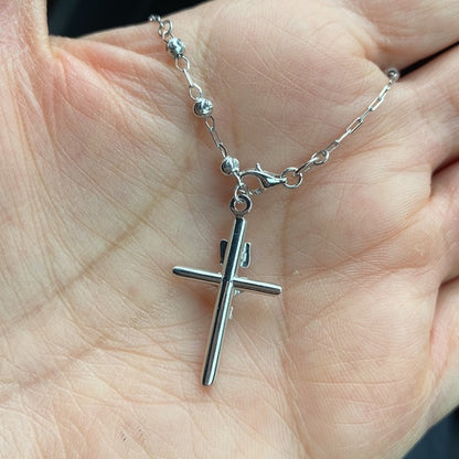 Silver cross necklace on a hand availabe on TX.ORO website.