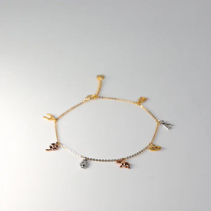 Gold anklet with various charms on a light gray background available on the TX.ORO website.