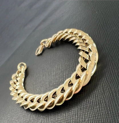 Gold chain bracelet on a dark textured surface available on the TX.ORO website.