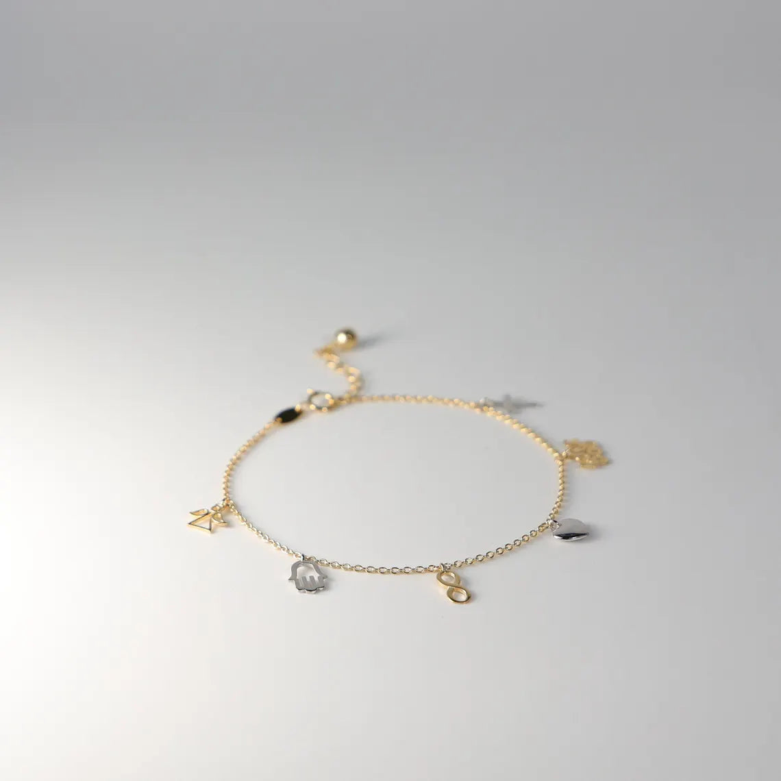 Gold bracelet with charms on a light gray background available on the TX.ORO website.