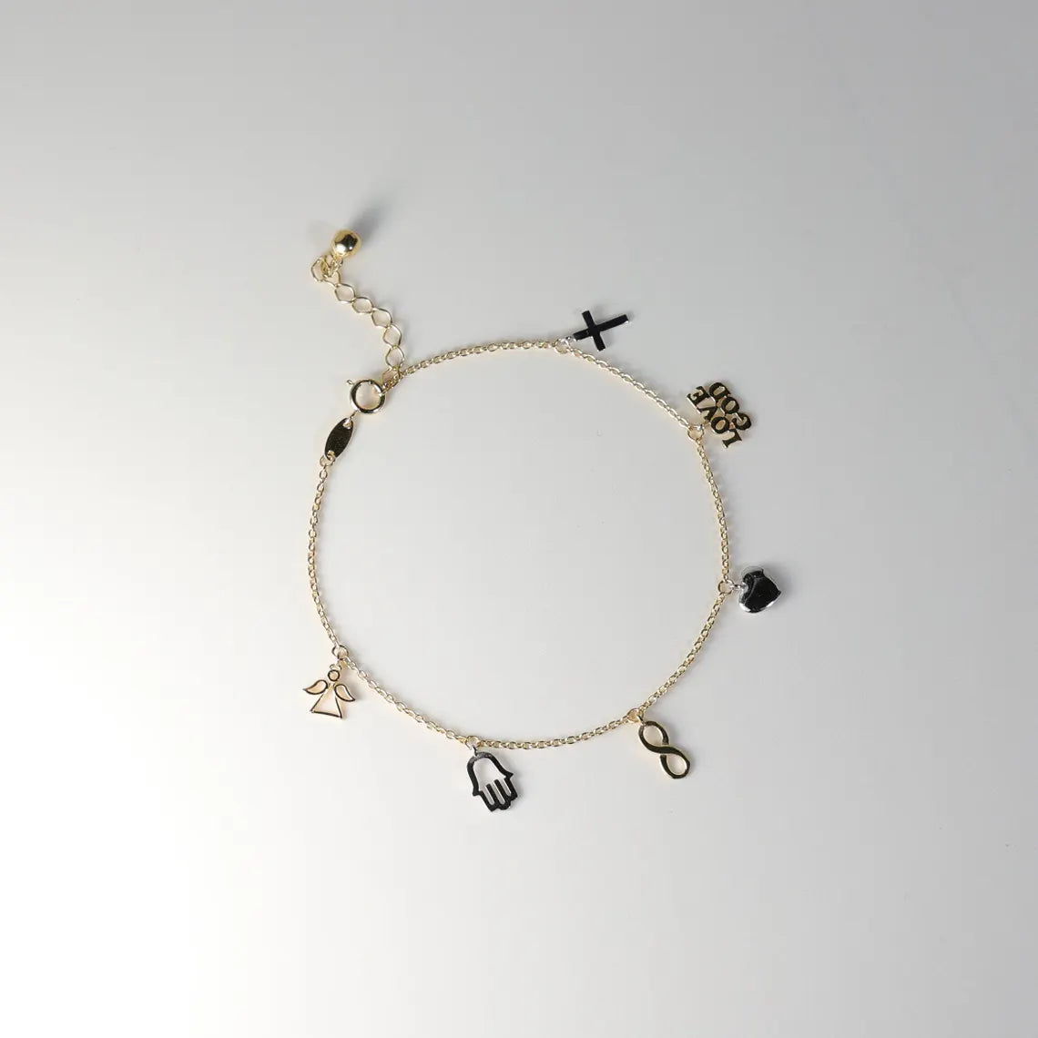 Gold bracelet with various charms on a white background available on the TX.ORO website.