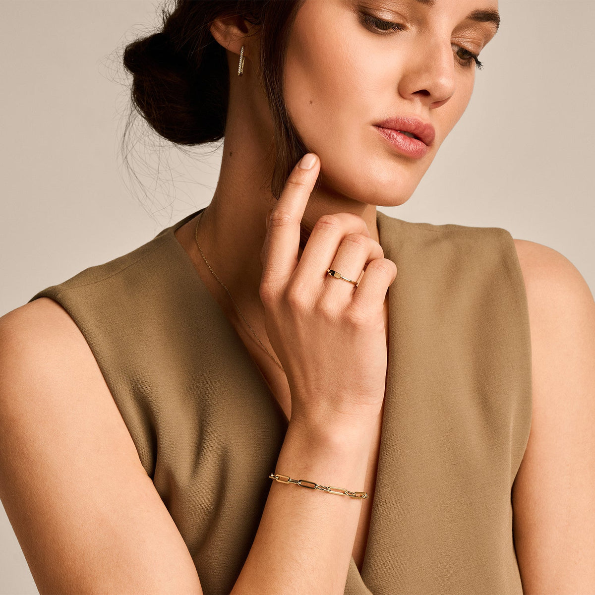 Woman wearing a gold bracelet and ring, with a neutral background available on the TX.ORO website.