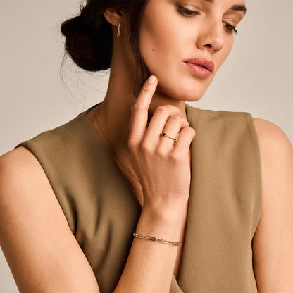 Woman wearing a gold bracelet and ring, with a neutral background available on the TX.ORO website.
