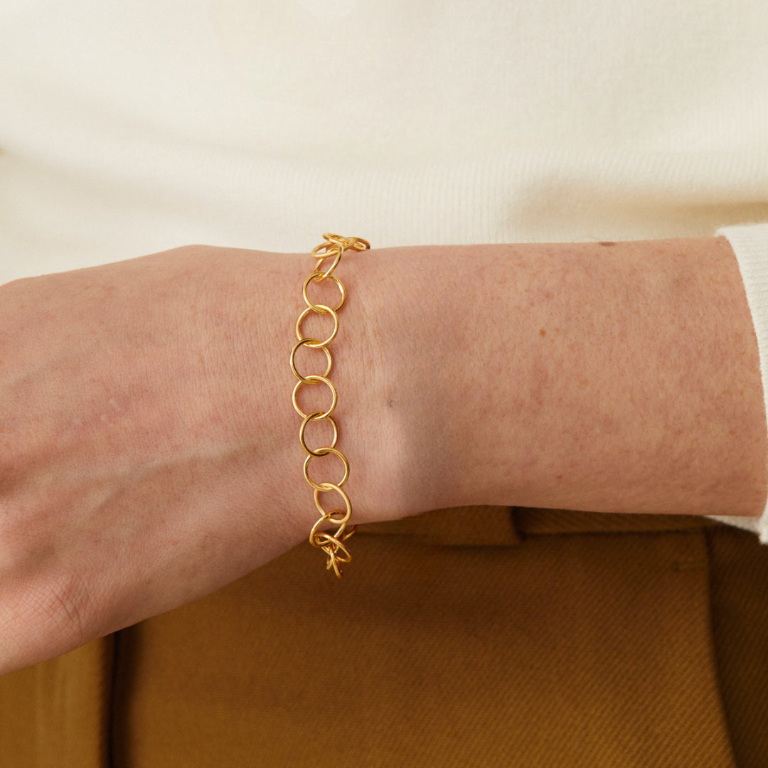 Gold chain bracelet on a person's wrist with a neutral background available on the TX.ORO website.