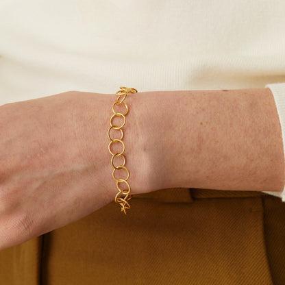 Gold chain bracelet on a person's wrist with a neutral background available on the TX.ORO website.