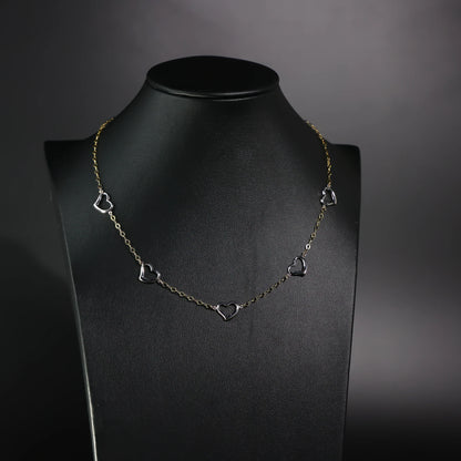 Necklace with heart-shaped pendants on a black mannequin against a dark background available on the TX.ORO website.