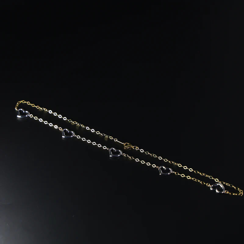 Gold chain with heart pendants on a black background available on the TX.ORO website.