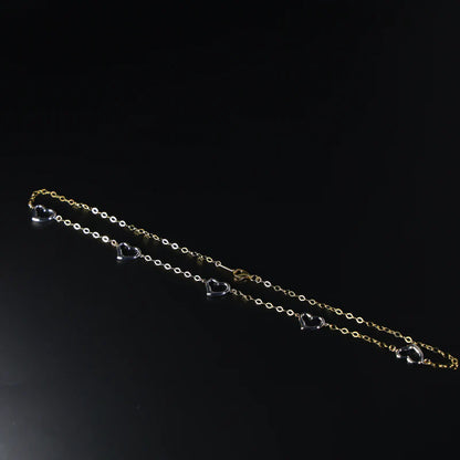 Gold chain with heart pendants on a black background available on the TX.ORO website.
