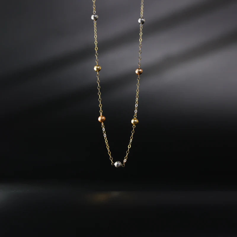 Necklace with small beads on a dark background available on the TX.ORO website.