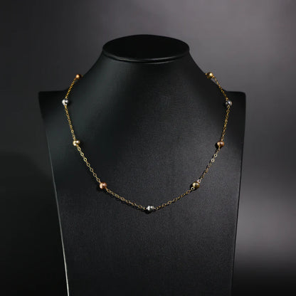 Necklace with beads on a black mannequin against a dark background available on the TX.ORO website.