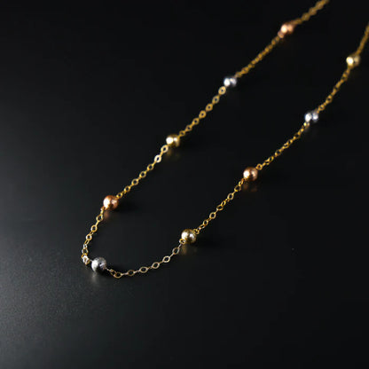 Gold chain necklace with small beads on a black background available on the TX.ORO website.
