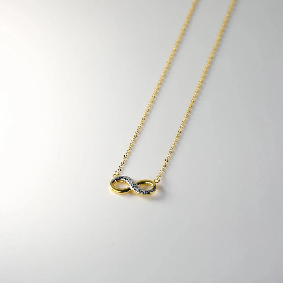 Gold infinity necklace on a light gray background available on the TX.ORO website.