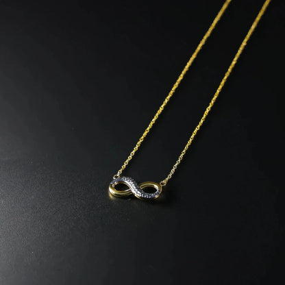 Gold necklace with an infinity symbol pendant on a black background available on the TX.ORO website.