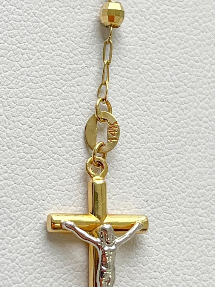 Gold cross pendant with Jesus figure on a white leather background availabe on TX.ORO website