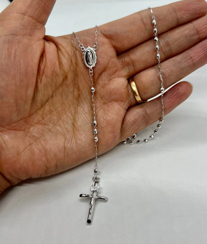 Silver rosary necklace held in a hand on a white background availabe on TX.ORO website.