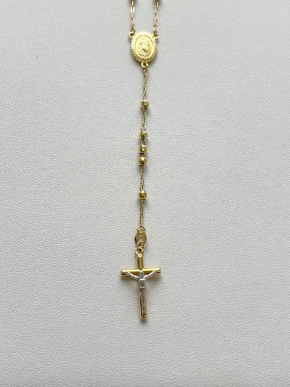 Gold rosary necklace on a light gray background availabe on TX.ORO website.