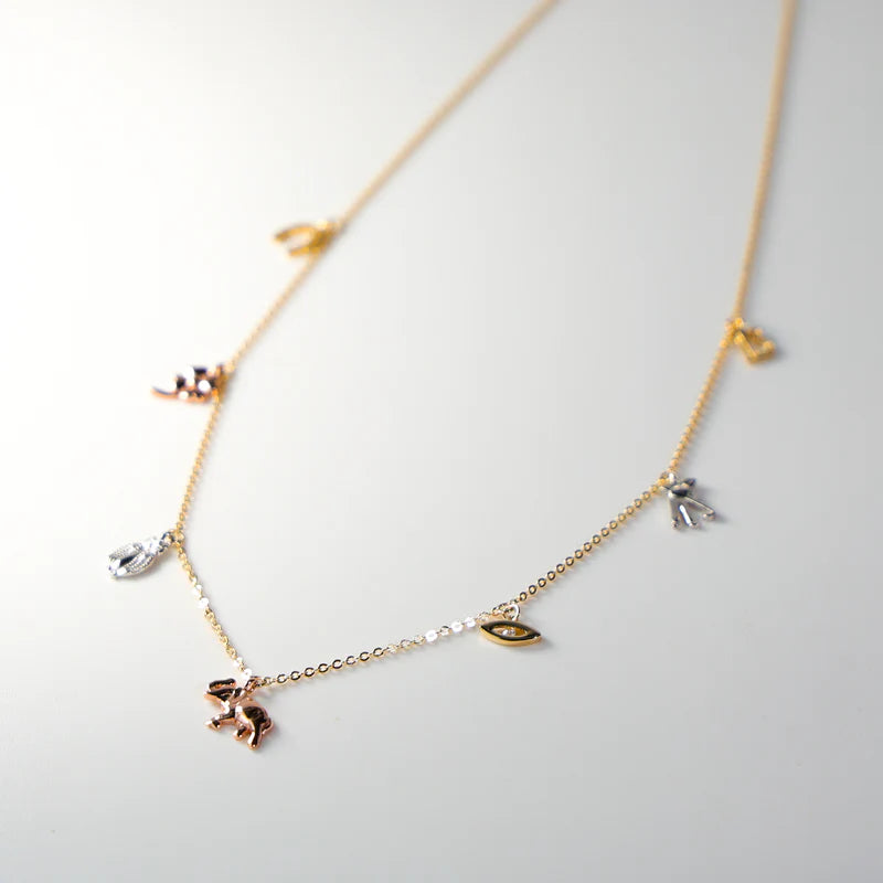 Gold necklace with various charms on a light gray background available on the TX.ORO website.