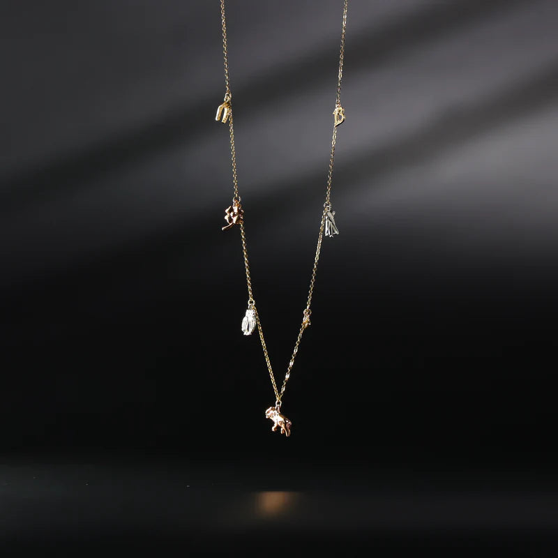 Delicate gold necklace with small pendants on a dark background available on the TX.ORO website.