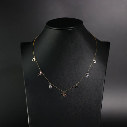 Necklace with small pendants on a black mannequin against a dark background available on the TX.ORO website.