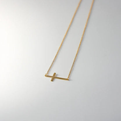 Gold necklace with a simple cross pendant on a light gray background available on the TX.ORO website.