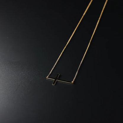 Gold necklace with a cross pendant on a black background available on the TX.ORO website.