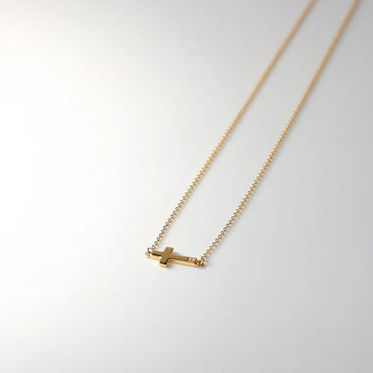 Gold necklace with a small pendant on a light gray background available on the TX.ORO website.