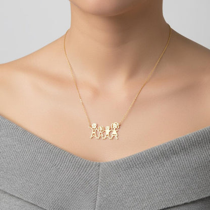 A close-up of a model wearing a delicate gold chain necklace with a pendant featuring three small connected figures, styled with a gray off-the-shoulder top.