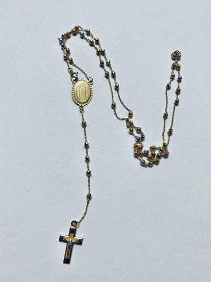 Rosary necklace with beads and a cross on a light gray background availabe on TX.ORO website.