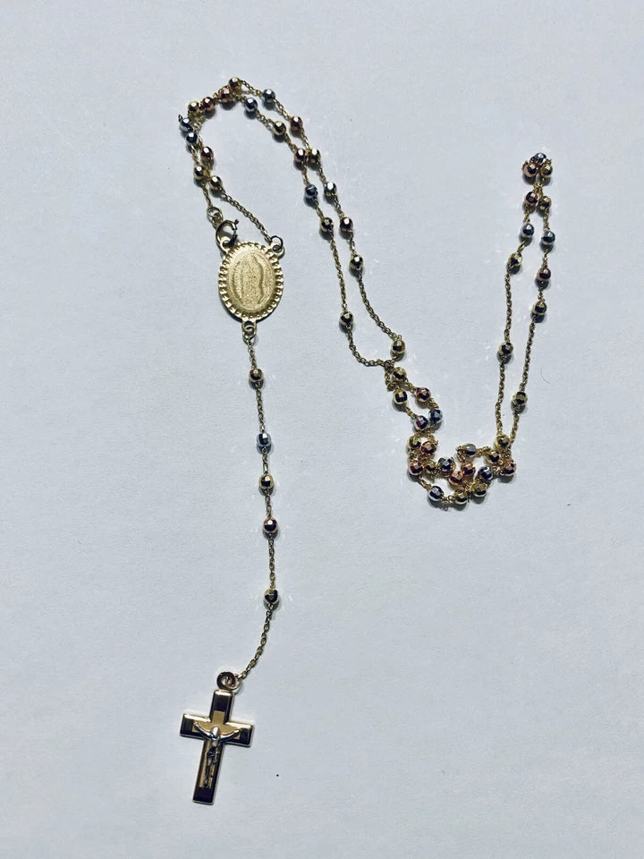 Rosary necklace with beads and a cross on a light gray background availabe on TX.ORO website.
