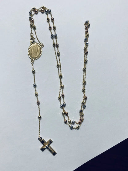 Rosary necklace with beads and cross on a light gray background availabe on TX.ORO website.