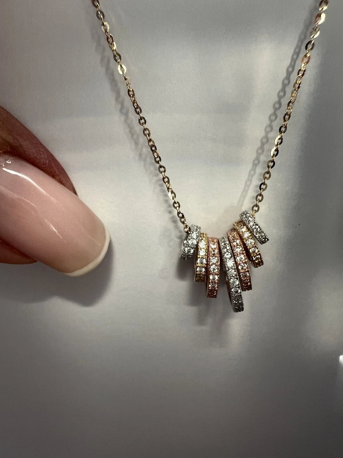 Necklace with diamond pendants held by a hand on a light background available on the TX.ORO website.