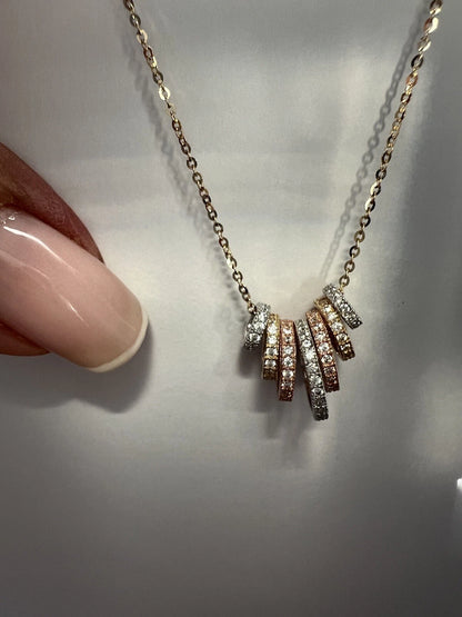Necklace with diamond pendants held by a hand on a light background available on the TX.ORO website.