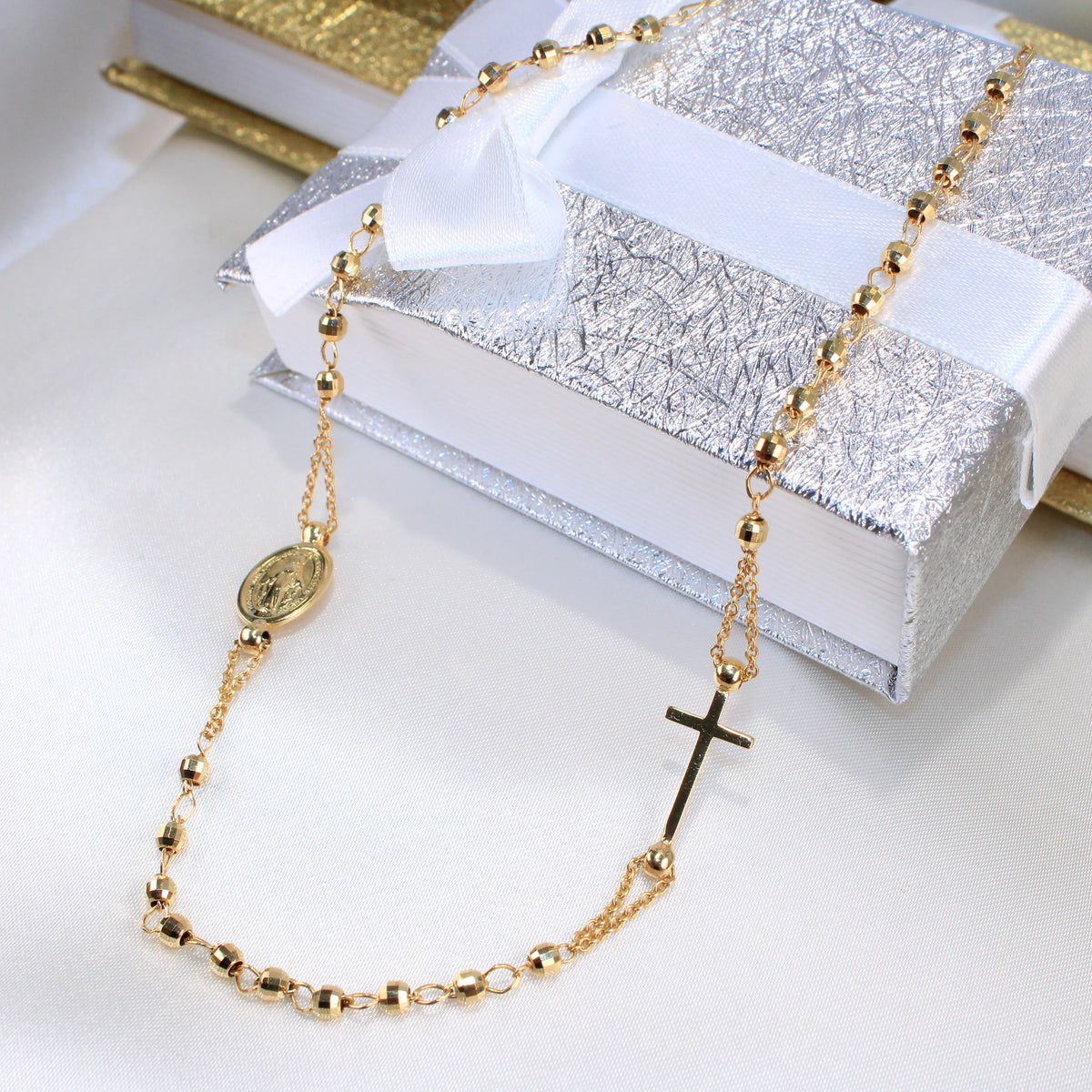 Gold necklace with a cross pendant on a white surface available on the TX.ORO website.