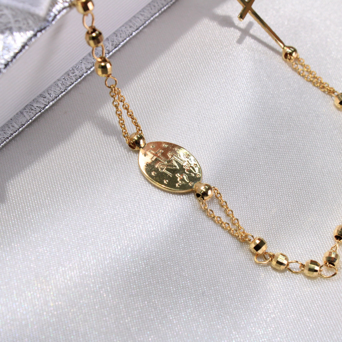 Gold bracelet with a decorative clasp on a light fabric background available on the TX.ORO website.