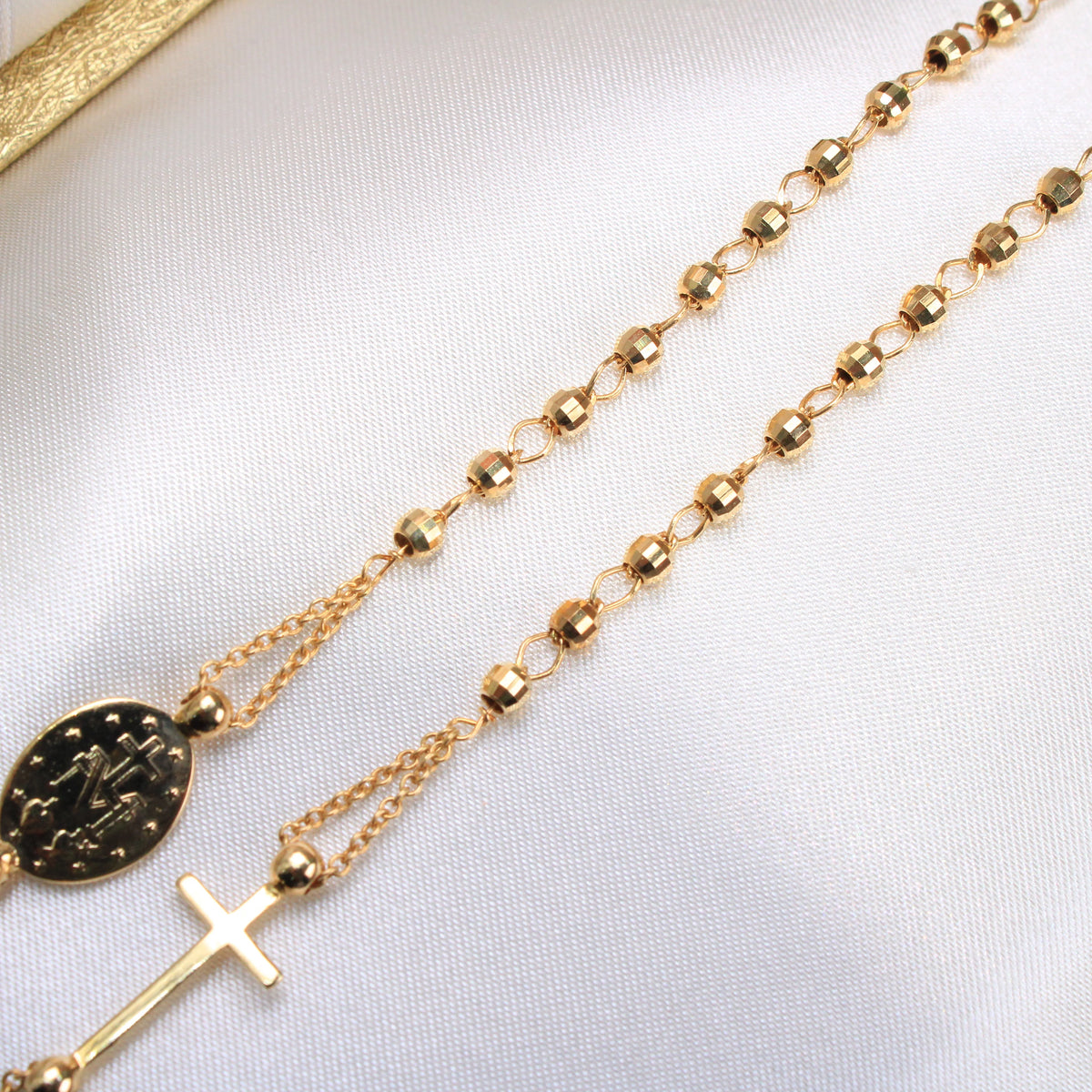 Gold rosary necklace on a white background available on the TX.ORO website.