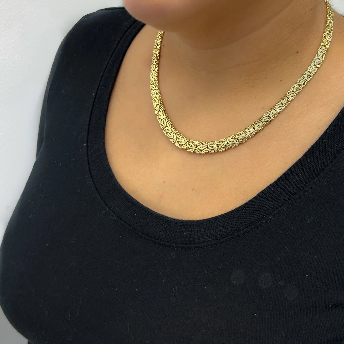 Gold chain necklace worn by a person on a black background available on the TX.ORO website.