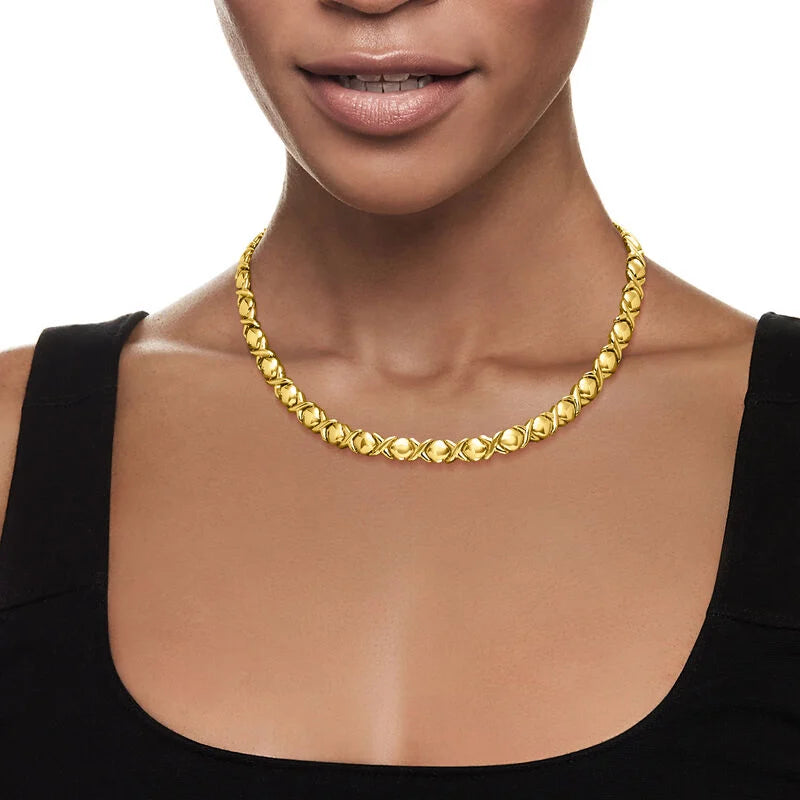 Woman wearing a necklace with a cross pendant on a plain background available on the TX.ORO website.