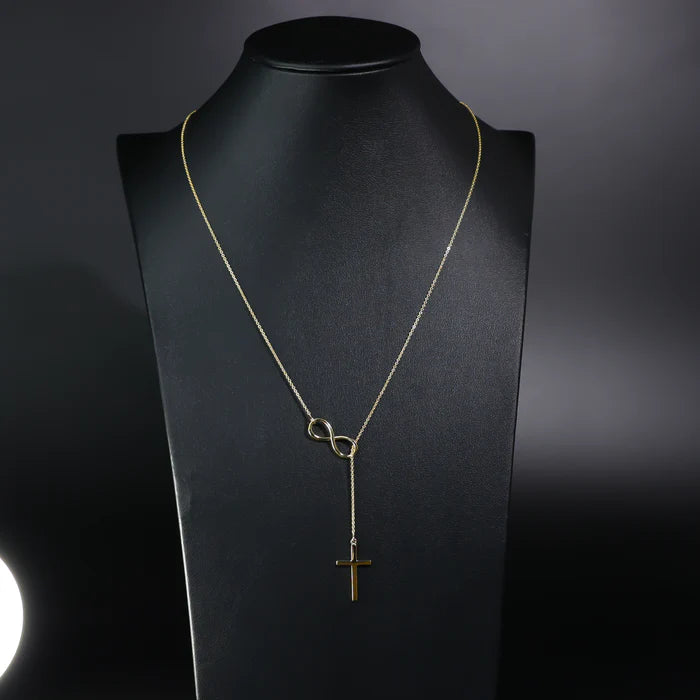 Gold necklace with infinity and cross pendants on a black mannequin bust available on the TX.ORO website.